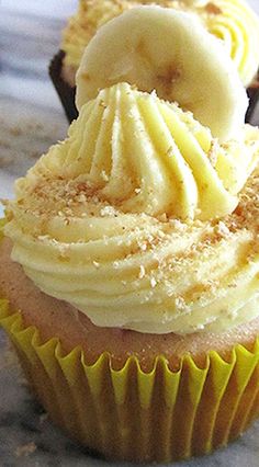 two cupcakes with white frosting and banana slices on top are sitting on a table