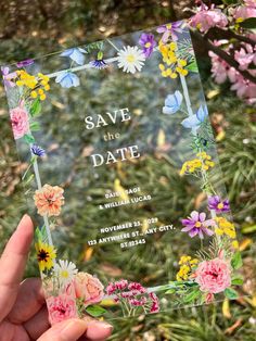 a person holding up a card with flowers on it and the words save the date