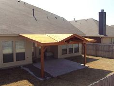 an outdoor patio with a wooden gazebo in the middle of it and grass on the ground