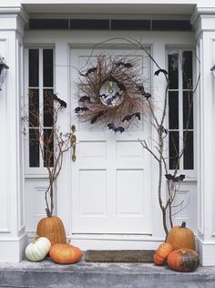 two pumpkins sitting in front of a white door with decorations on the outside and inside