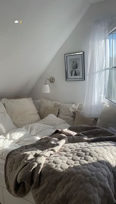 an unmade bed sitting in the corner of a room next to a large window