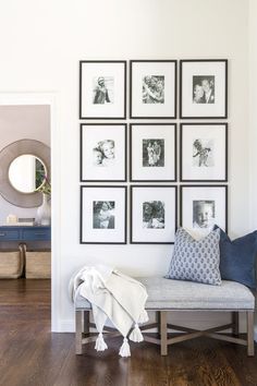 a white room with pictures on the wall and a bench in front of it,