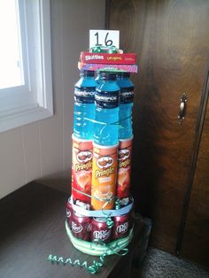 a stack of soda cans sitting on top of a wooden table next to a window