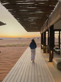 a woman walking down a long wooden walkway