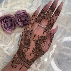 a woman's hand with henna on it and two flowers in the background