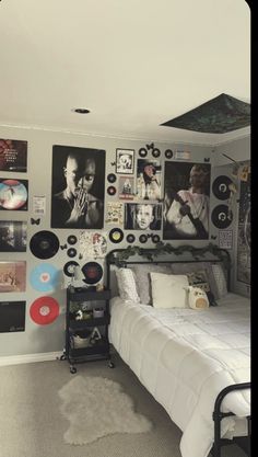 a bed sitting in a bedroom next to a wall covered with pictures and record discs