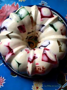 a bundt cake with white frosting and colorful toppings on a blue plate