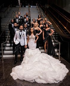 a group of people in formal wear posing for a photo on the stairs at an event