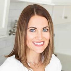 a woman in a white shirt is smiling at the camera and she has blue eyes