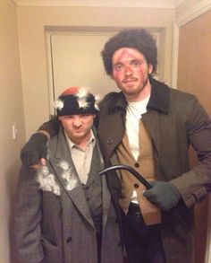 two men dressed up in period costumes posing for the camera with one holding an umbrella