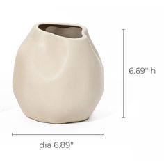 a large white vase sitting on top of a table next to a measuring ruler with the measurements