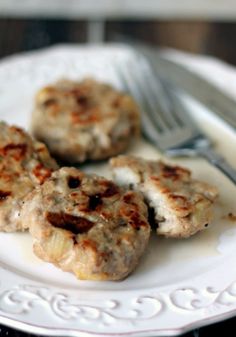 three hamburger patties on a white plate with a fork