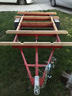 a red cart sitting on top of a lush green field next to a white car