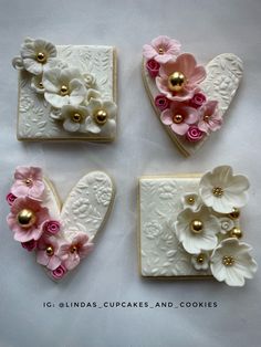 four heart shaped cookies decorated with pink and white flowers on top of each cookie in the shape of a heart