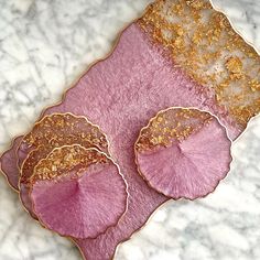 three pink and gold plates sitting on top of a marble counter