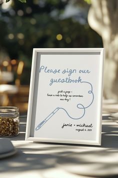 there is a sign on the table that says please sign our guest book with a pen in it