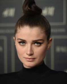 a close up of a person with a bun in her hair and wearing a black turtle neck top