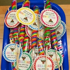 there are many spoons in the tray with name tags on them, and one is filled with candy