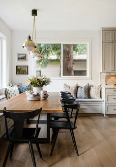 a dining room table with chairs and a bench in front of the window next to it