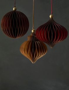 three red and brown paper lanterns hanging from strings on a gray background with gold accents