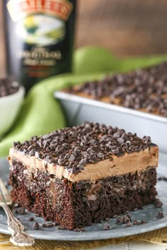 a piece of chocolate cake on a plate with a bottle of beer in the background