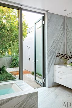 a bathroom with a tub, sink and large glass doors leading to an outside shower area