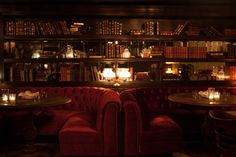 two red booths with tables and chairs in front of bookshelves filled with books