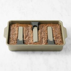 three slices of bread in a loaf pan on a marble counter top with two forks