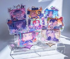 an assortment of anime coasters on display in a clear case with white light coming through the window