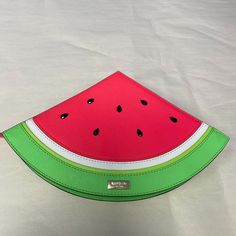 a watermelon shaped purse sitting on top of a white sheet