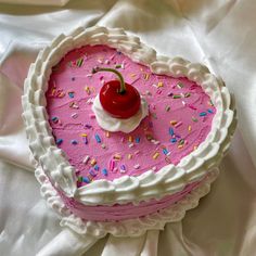 a heart shaped cake with sprinkles and a cherry on top