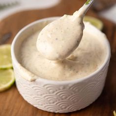 a spoon full of white sauce with limes around it