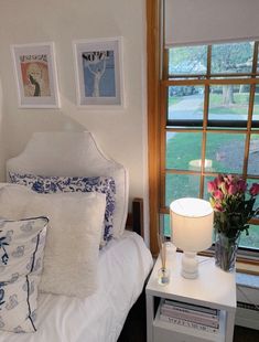 a white bed sitting next to a window covered in pillows and blankets on top of it