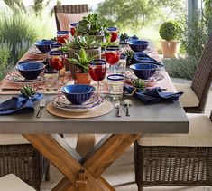 a dining table set with blue and red dishes, place settings and utensils