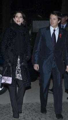 the man and woman are walking down the street at night, one is wearing a black coat