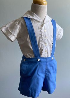 "This is a remarkable set for boys, probably from the 1930's/very early 40's. It is remarkable as the two pieces, shirt and shorts, are sewn entirely by hand! Not a machine stitch used.                 The shirt is white cotton and has a longer than usual shirt tail to keep it tucked in. It has a wide front placket which is closed by six buttons. A narrow  waistband provide buttons for the shorts.  The neckline is a V, with a wide spread collar. Sleeves are short with plain, wide cuffs.  Edges o Vintage Boys Clothes, Snow White Dresses, Hand Smocked Dress, Aesthetic Galaxy, Shirt And Shorts, Vintage Boys, Wide Cuff, Dress Purchase, Clothing Sets