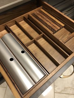 an open drawer with two silver items in it on top of a wooden countertop