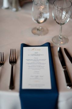 the table is set with silverware, wine glasses, and menu cards on it