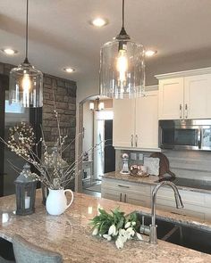 a kitchen with marble counter tops and stainless steel appliances, along with pendant lights over the sink