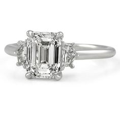 an emerald cut diamond ring with three stone shoulders and two baguetts on the band