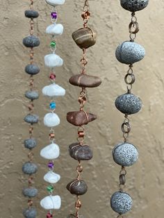 a group of rocks hanging from chains on a wall next to a cement wall,