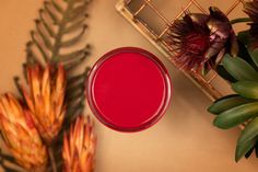 a red liquid in a glass next to some flowers