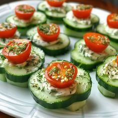 cucumbers with tomatoes and herbs on them are arranged on a white platter