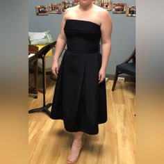 a woman in a black dress standing on a hard wood floor