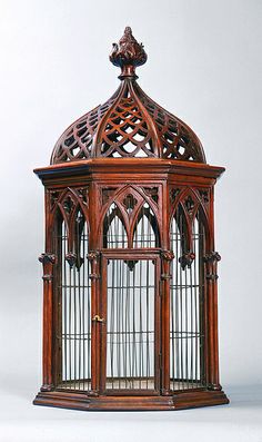 an ornate wooden birdcage with intricate carvings on the top and sides, set against a white background