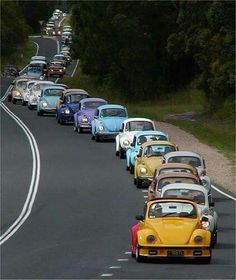 a line of cars driving down a road with trees in the background