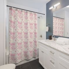 a bathroom with a sink, toilet and shower curtain covered in pink flowered fabric