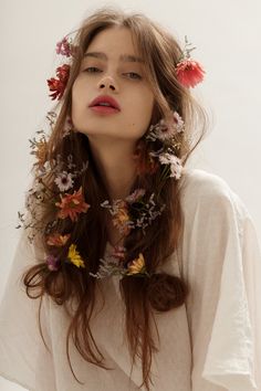 a woman with flowers in her hair is wearing a white shirt and flower garland around her neck