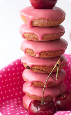 a stack of doughnuts with pink icing and cherries