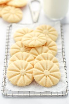 some cookies are on a cooling rack next to a glass of milk